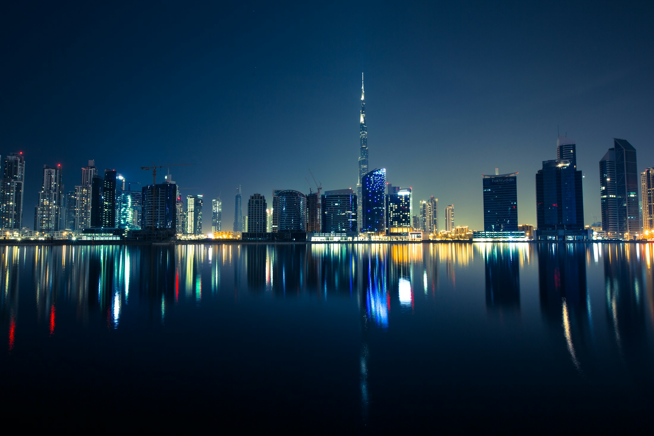 Dubai skyline reflected in still water at night